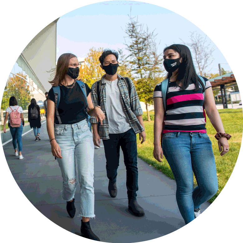 Three people with masks on walking together.
